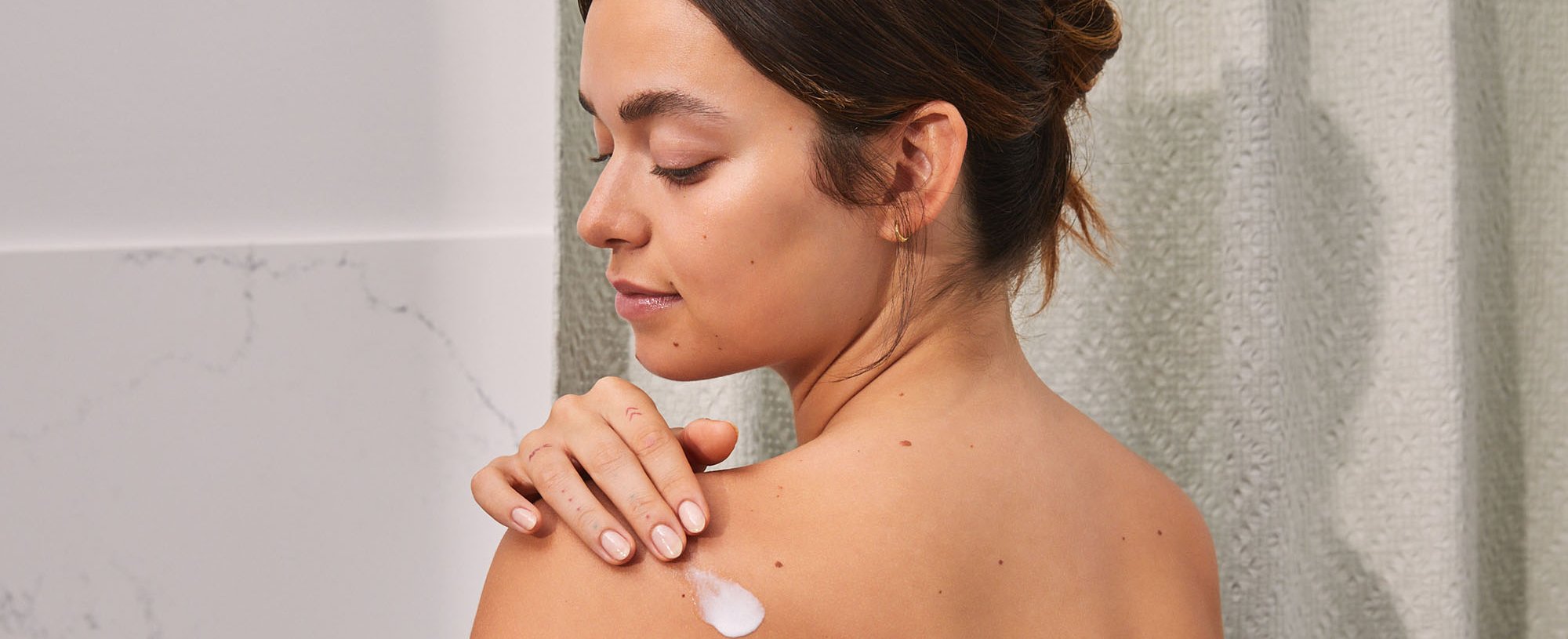 Person Applying Lotion On Their Back