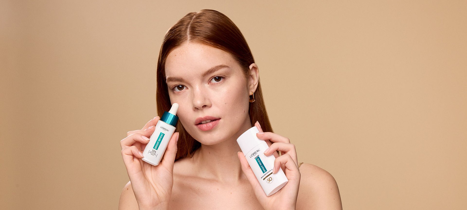 Woman holding loreal niacinamide serum and SPF