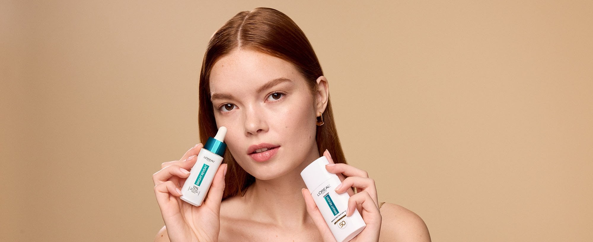 Woman holding loreal niacinamide serum and SPF