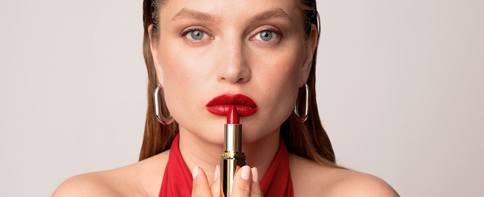 A woman applying red lipstick to lips