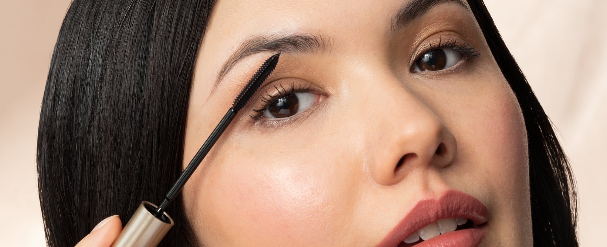 A woman applying mascara to her eyelashes